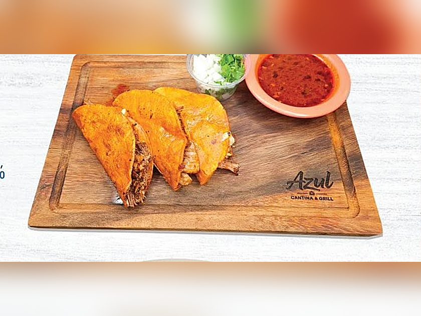 Quesabirrias on a wooden board with consommé and salsa